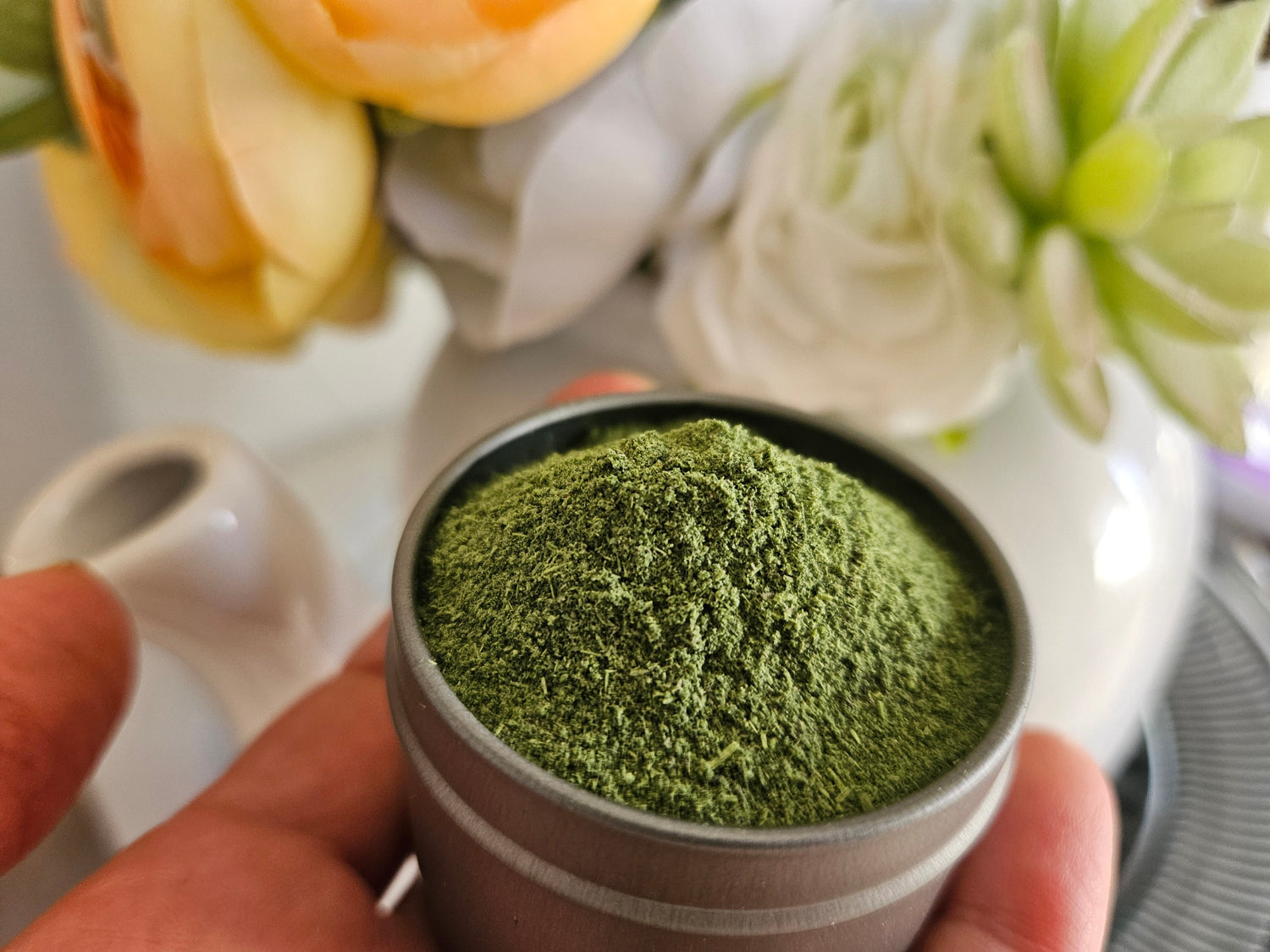 Microgreen powder in a tin is being held in hand.